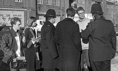 PICTURE: Rick Gibson talking to two police officers, two journalists and a lawyer (back to camera.)