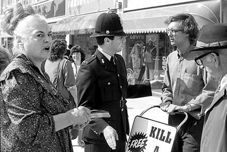 Black and white photo of policeman arresting Gibson while Ms. Piddington and a pedestrian watch