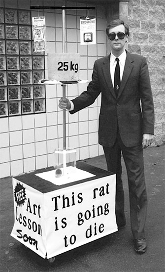 Black and white publicity photo of Gibson standing beside the rat crushing art machine
