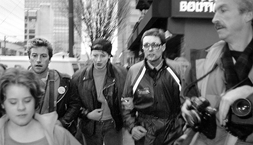 Black and white photo of Paddy, Susi and Gibson walking with linked arms