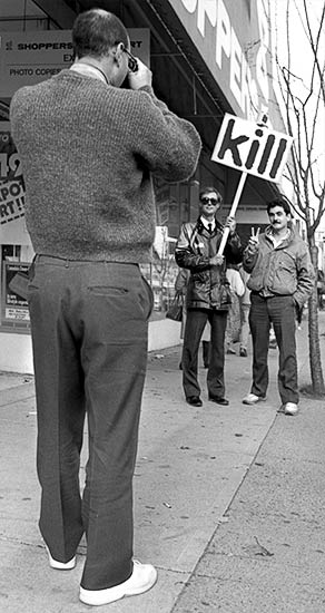 PICTURE: black and white photo of a tourist from Californian taking a picture of Gibson with the man's friend. Photograph by Tom Buhr.